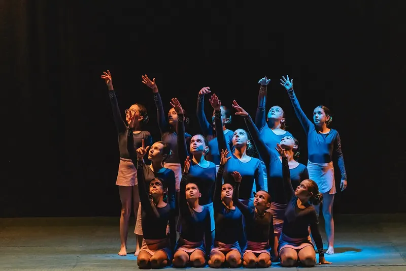 Classe de Competição em pose final, braços levantados, sob luz azul